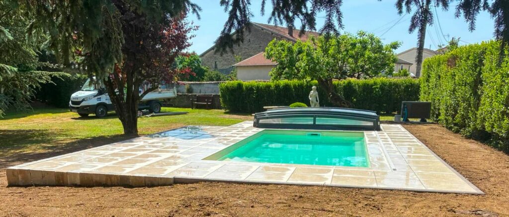 Piscine enterrée avec plage pavée et abri bas