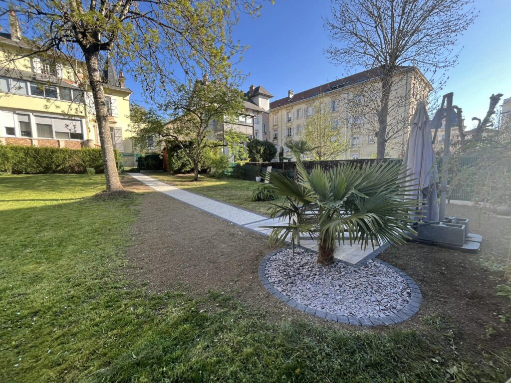 Chemin de jardin et massif minéral autour d’un palmier