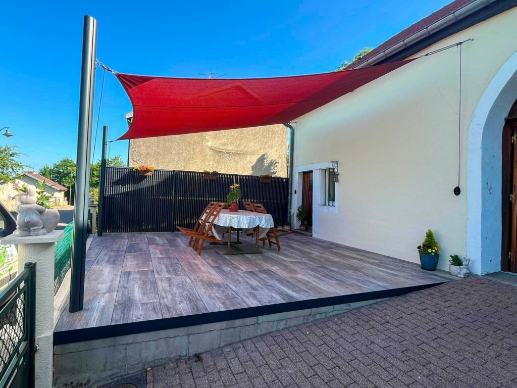 Terrasse effet bois avec voile d’ombrage rouge